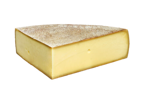 Größeres Stück Bergalmkäse mit goldbrauner Rinde und wenigen kleinen Löchern im Teig