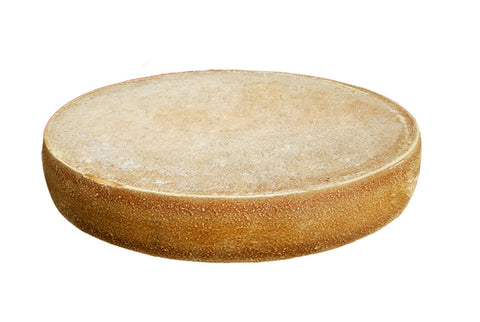Ganzer runder Laib Bergalmkäse schräg von oben mit heller, leicht bemehlter Naturrinde