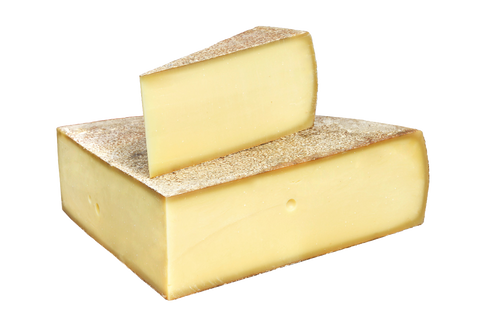 Zwei Stücke goldgelber Bergkäse mit genarbter Rinde, ein Keil auf einem Block, vor weißem Hintergrund