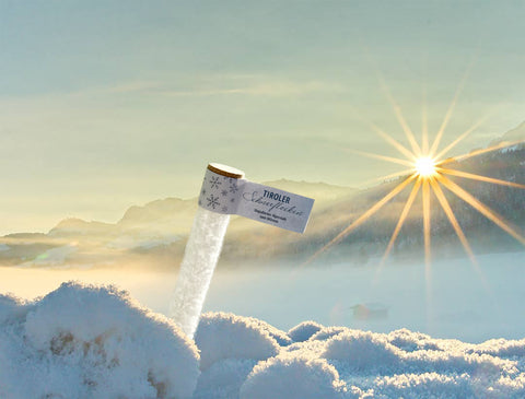 Röhrchen Tiroler Schneeflocken Alpensalz steckt im echten Schnee vor winterlicher Berglandschaft mit strahlender Sonne